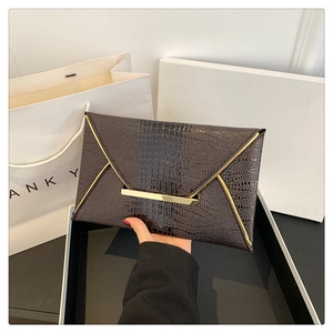 Dettaglio pochette marrone scuro stampa coccodrillo con finiture in metallo dorato a V