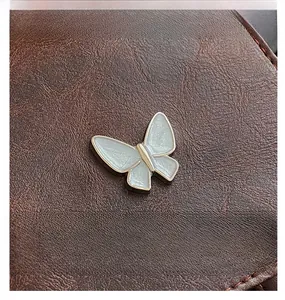 Close-up of brown litchi grain leather with a silver pearlescent butterfly buckle