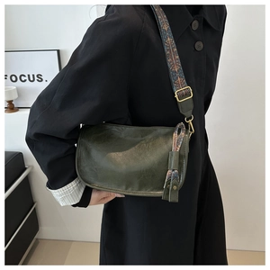 Sac polochon cuir vert foncé avec large bandoulière brodée ethnique et détails pompons
