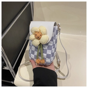 Detail of checkered mini crossbody bag with a large yellow floral charm and white strap
