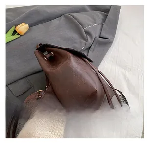 Side view of dark brown vintage faux leather backpack with drawstring and metal strap buckle