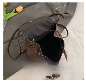 Internal view of dark brown PU leather backpack with drawstring closure and metal snap