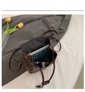 Detail view of the brown retro backpack's interior capacity holding a tablet and cosmetics