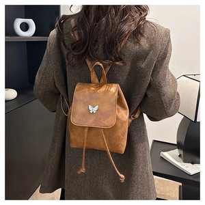 Close-up of vintage brown leather backpack with silver butterfly detail and drawstring