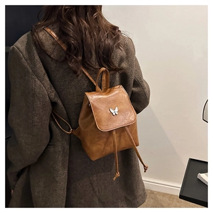 Brown mini vintage faux leather backpack with silver butterfly detail worn by model