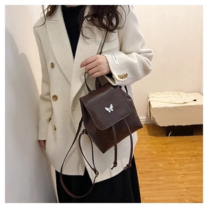 Detail of coffee brown leather backpack featuring a silver butterfly buckle and drawstring