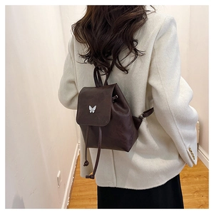 Detail of mini dark brown vintage backpack with white butterfly metal buckle on light blazer
