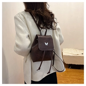 Detailed back view of a mini dark brown backpack with white butterfly on tweed coat