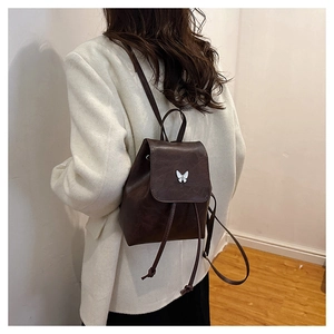 Detail of a vintage dark coffee mini backpack with silver butterfly hardware on model