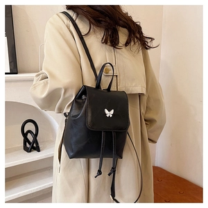 Detailed back view of a mini black leather backpack with a silver butterfly metal clasp