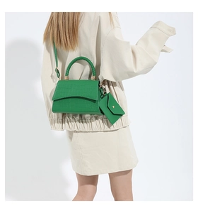 Detalle del bolso verde esmeralda con relieve de cocodrilo, asa trenzada y mini monedero