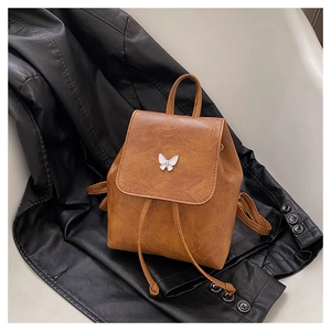 Detail view of brown vintage mini backpack with white butterfly metal accessory and PU leather