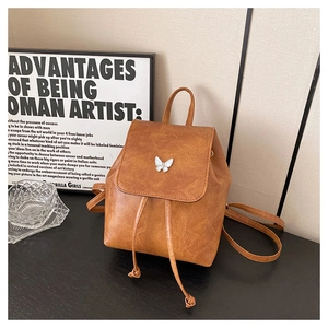Detail of vintage brown mini backpack featuring a metal butterfly and drawstring closure
