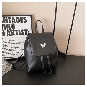 Close-up of black PU leather mini backpack featuring a white enamel butterfly buckle