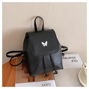 Close-up of black leather backpack featuring a white butterfly hardware and drawstring