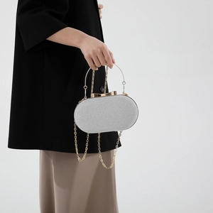 Silver sequin round evening bag with circular metal handle and bow clasp on gray background
