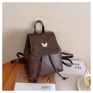 Detail of dark brown vintage PU leather backpack with a white butterfly ornament on the flap