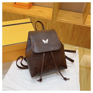 Detail of dark brown vintage faux leather backpack featuring a white butterfly buckle