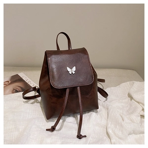 Detail of dark brown PU leather backpack with butterfly buckle and drawstring closure