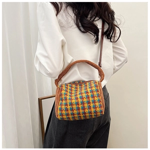 Detail of tricolor houndstooth crossbody bag with orange plush trim and leather strap