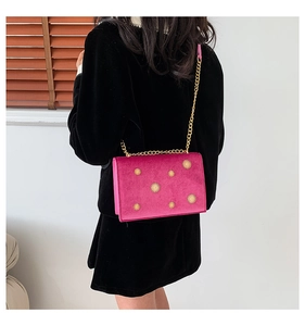 Detail of rose red velvet crossbody bag with golden sunflower rivets on a metal chain