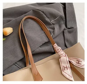 Detail of apricot tote bag with brown straps and H-pattern silk scarf on a grey blazer