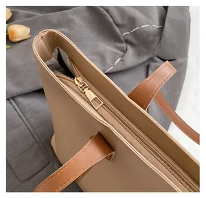 Close-up of smooth gold zipper and stitching detail on minimalist beige tote bag
