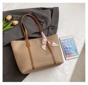 Detail view of large khaki tote bag holding a tablet with a decorative silk scarf