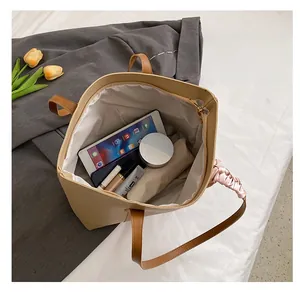 Detail showing spacious khaki tote bag interior holding tablet and cosmetics
