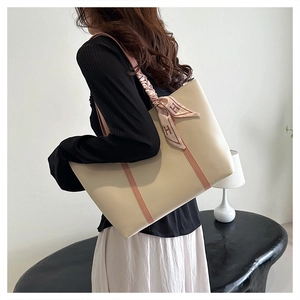 Detail of cream tote bag with pink stripes and decorative silk scarf shown on model