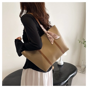 Detail of camel leather tote bag with decorative H-pattern silk scarf handle accent