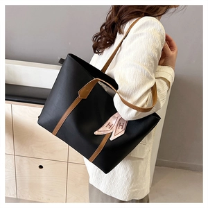 Detail of black tote bag with brown trim and decorative pink H-print silk scarf on handle