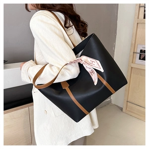 Macro detail of black leather tote bag with brown straps and silk scarf on model