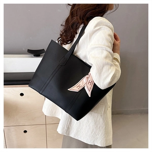 Detail view of large black tote bag with decorative silk scarf on slender shoulder straps