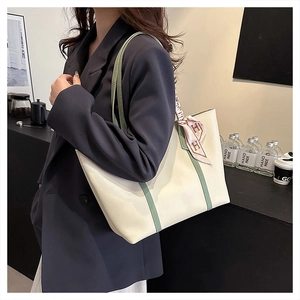 Detail of cream and green tote bag with pink silk scarf worn over a grey blazer
