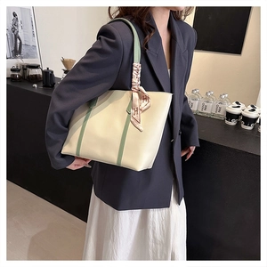 Close-up of minimalist beige tote bag with green straps and silk scarf detail