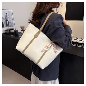 Chic cream tote bag with contrast brown straps and stylish silk scarf detail on handle