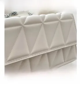 Close-up of white geometric quilted faux leather bag with silver metal chain strap