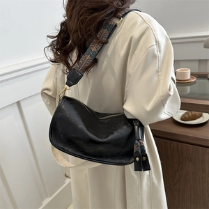 Grand sac hobo noir à bandoulière géométrique porté par un mannequin en intérieur