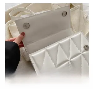Detail shot of a white quilted crossbody bag showing the magnetic hardware closure