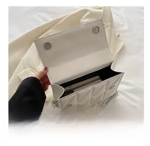 Interior capacity detail of white quilted crossbody bag with silver chain and phone inside