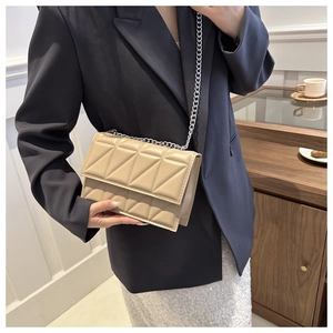 Close-up of beige quilted chain bag with elegant triangle pattern stitching detail