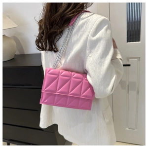 Pink quilted shoulder bag with silver chain strap shown worn on a white blazer