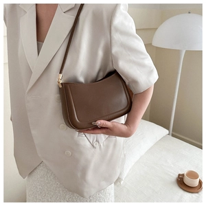 Detail of a dark brown vintage shoulder bag with fine leather texture and golden buckle