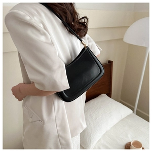 Classic black minimalist underarm bag made of smooth PU leather shown on a shoulder