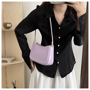 Detail of light purple leather underarm bag with U-shaped design and gold metal hardware