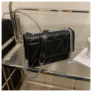 Detail of black rectangular crossbody bag with silver chain and triangle quilted texture