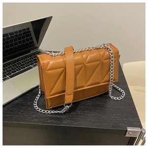 Detail of caramel geometric quilted crossbody bag on wooden desk with silver laptop