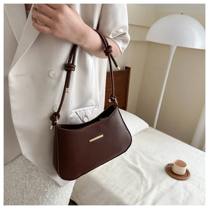Detail of a brown leather shoulder bag with gold metal hardware and knotted handle