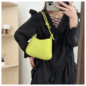 Detail of neon green leather shoulder bag featuring knotted strap and gold metal hardware